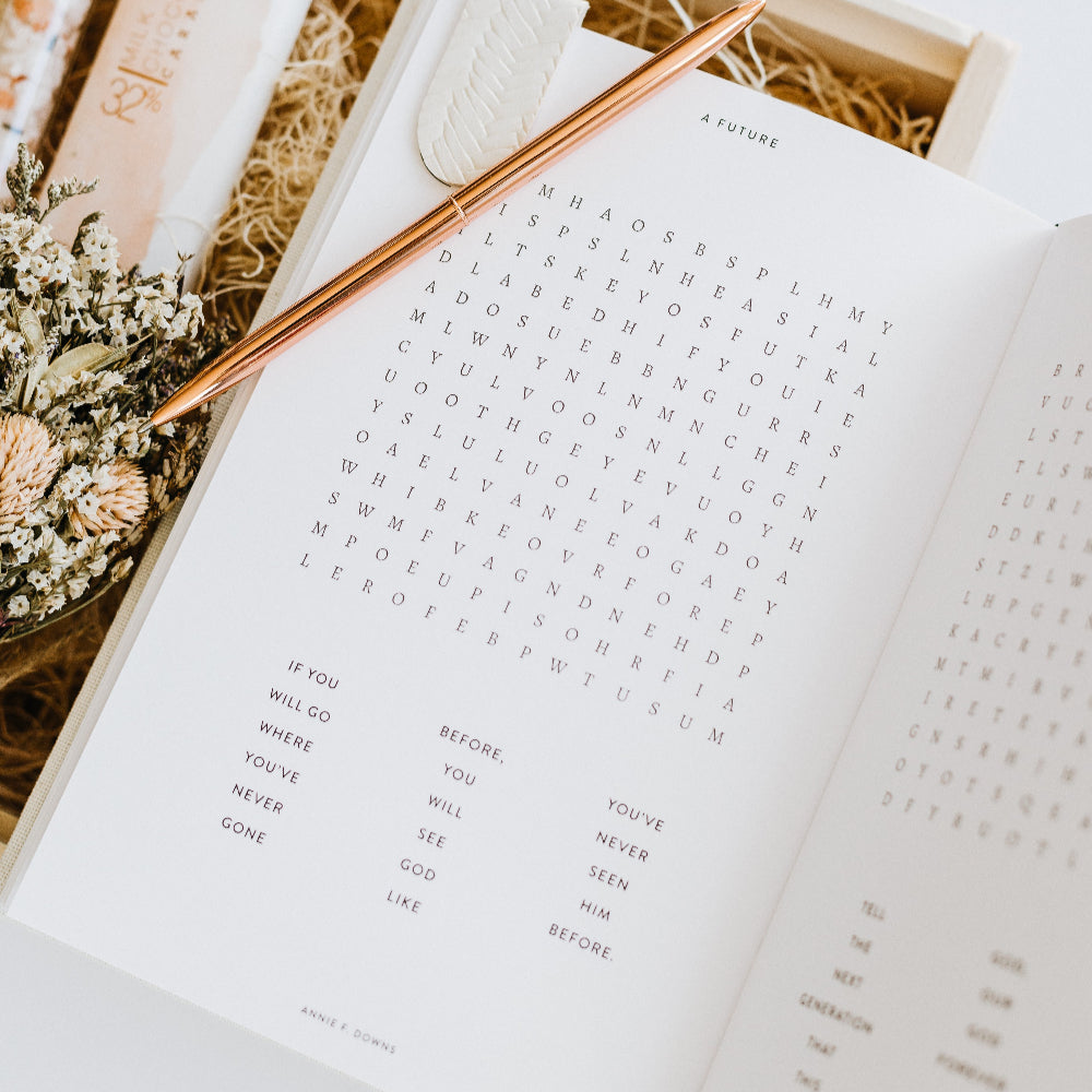 Open book with a pen and dried flowers on a white surface