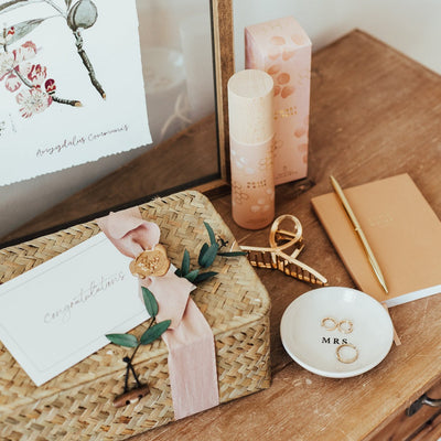 A luxury gift box for a bride-to-be, newly wed or a long-time married friend. This gift box includes a notebook, gold pen, Honey & Rose room spray, a "Mrs." stoneware ring dish, and a gold hair claw. Packaged in either a seagrass gift box or a wooden keepsake gift box.