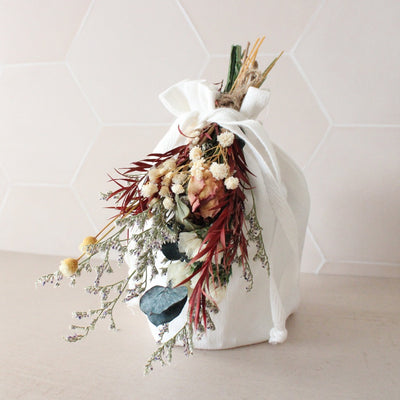 Organic cotton gift bag with a mini bouquet of dried flowers tied at the top.