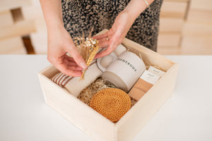 Photo of a woman placing a small bouquet of flowers into a luxury, customizable wooden gift box.